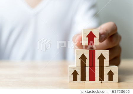 Hand arranging wood block stacking as step stair with arrow up 63758605