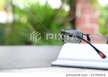 Reading glasses on top of an open book. Garden or Reading glasses on top of an open book. Garden or 63760928