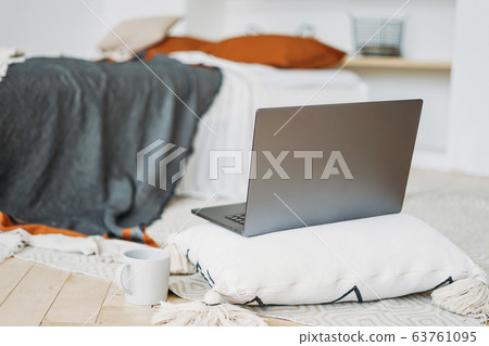 Opened laptop notebook on pillow with cup of tea 63761095