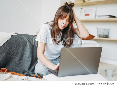 Working young brunette woman freelancer with laptop at home Working young brunette woman freelancer with laptop at home 63761096