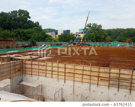 Building floor slab under construction. Construction workers fabricating the timber formwork and installing the steel reinforcement bar. Building floor slab under construction. Construction workers fabricating the timber formwork and installing the steel reinforcement bar. 63762415