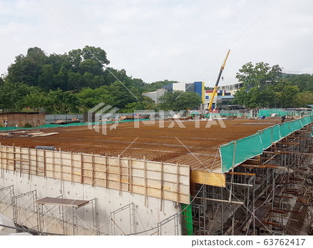 Building floor slab under construction. Construction workers fabricating the timber formwork and installing the steel reinforcement bar. Building floor slab under construction. Construction workers fabricating the timber formwork and installing the steel reinforcement bar. 63762417
