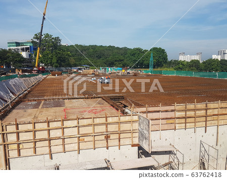 Building floor slab under construction. Construction workers fabricating the timber formwork and installing the steel reinforcement bar. Building floor slab under construction. Construction workers fabricating the timber formwork and installing the steel reinforcement bar. 63762418