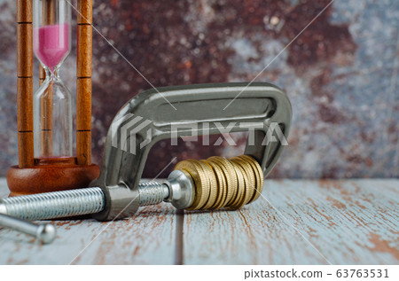 stacking coin squeezing in a G-clamp as a financial crisis concept 63763531