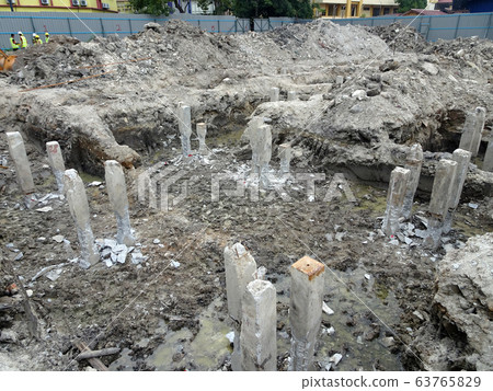 Square precast concrete pile at the construction site. Driven to soil using concrete pile machine. Square precast concrete pile at the construction site. Driven to soil using concrete pile machine. 63765829