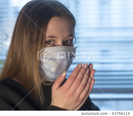 Virus spreading. Young woman looking at the camera sneezing or coughing in a protective medical face mask 63766218