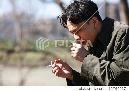 A man who smokes a cigarette 63766617