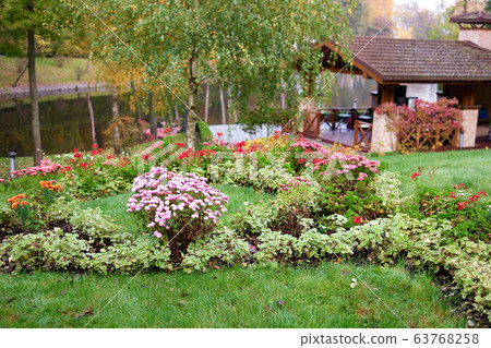 Park landscape with flowers, pond and gazebo. 63768258