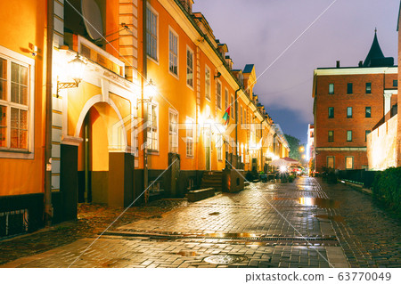 Riga, Latvia. Facades Of Old Famous Jacob's Barracks And Part Of Old The City Wall In Torna Street In Lighting At Evening Or Night Illumination In Old Town. 63770049