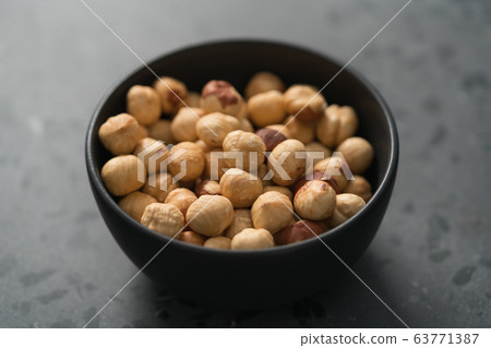 roasted hazelnuts in black bowl on terrazzo countertop 63771387