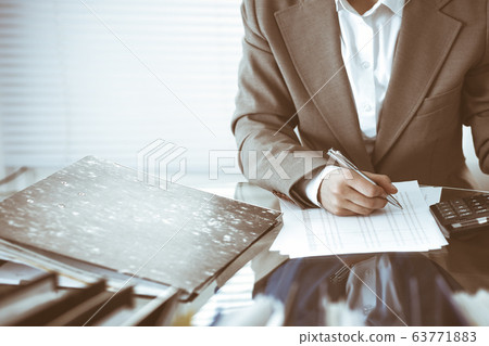 Bookkeeper woman or financial inspector making report, calculating or checking balance, close-up. Business, audit or tax concepts Bookkeeper woman or financial inspector making report, calculating or checking balance, close-up. Business, audit or tax concepts 63771883