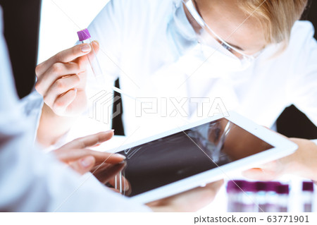 Coronavirus pandemic. Professional female scientist in protective eyeglasses researching tube in laboratory. Concepts of medicine and virus protection Coronavirus pandemic. Professional female scientist in protective eyeglasses researching tube in laboratory. Concepts of medicine and virus protection 63771901