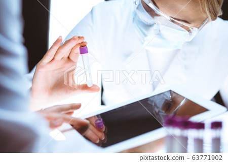 Coronavirus pandemic. Professional female scientist in protective eyeglasses researching tube in laboratory. Concepts of medicine and virus protection Coronavirus pandemic. Professional female scientist in protective eyeglasses researching tube in laboratory. Concepts of medicine and virus protection 63771902