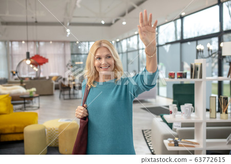 Blonde woman in a blue dress waving her hand Blonde woman in a blue dress waving her hand 63772615