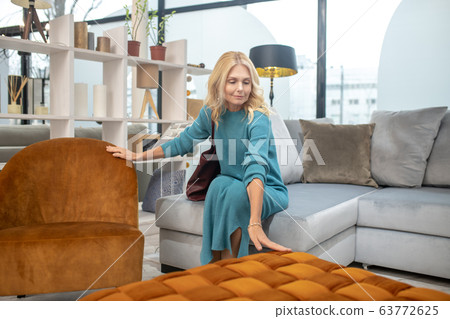 Blonde woman in a blue dress touching the furniture Blonde woman in a blue dress touching the furniture 63772625