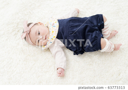 七個月大的女孩躺在她的背上 63773313