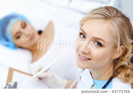 Female doctor and young woman patient in hospital. Physicians examine girl lying at the bed, view from above 63773768