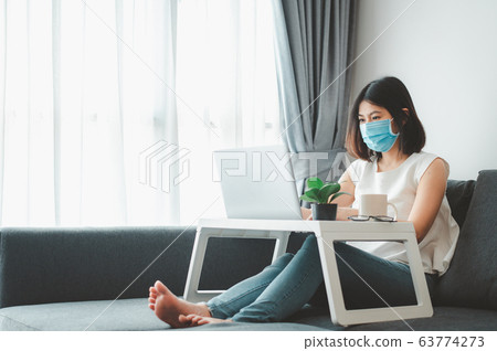 Asian woman wearing face mask working at home Asian woman wearing face mask working at home 63774273