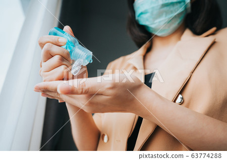 woman wearing face mask using alcohol gel woman wearing face mask using alcohol gel 63774288
