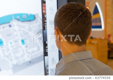 A man near the interactive map of the supermarket. 63774550