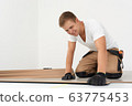 Male worker installing laminate flooring 63775453