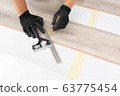 Worker hands installing timber laminate floor. 63775454