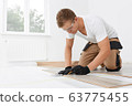 Repairman laying laminate flooring at home 63775455