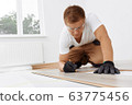 Handyman installing new laminated wooden floor 63775456