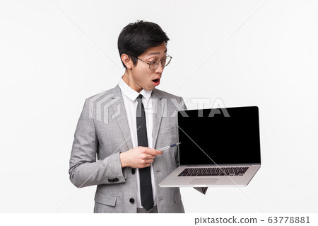Waist-up portrait of impressed, excited asian male entrepreneur astonished with good diagram chart, great income, looking with dropped jaw at laptop display, reading shocking info, white background Waist-up portrait of impressed, excited asian male entrepreneur astonished with good diagram chart, great income, looking with dropped jaw at laptop display, reading shocking info, white background 63778881