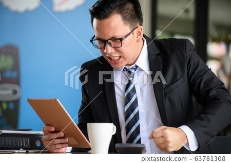 Angry businessman get fired message on tablet 63781308