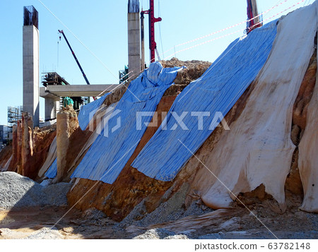 The geotextile fabric is spread over the surface of the slope to prevent erosion. Also to temporarily stabilize the slope before the permanent stabilization work done. 63782148