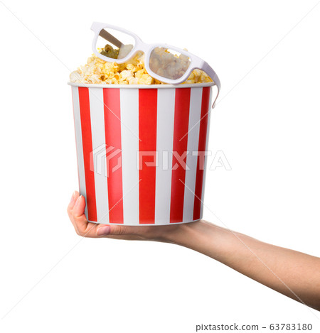 Woman hand holding striped bucket with popcorn and Woman hand holding striped bucket with popcorn and 63783180