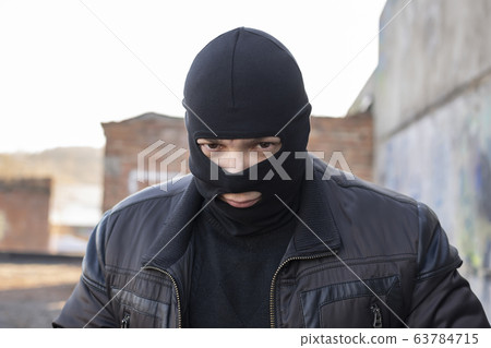 a bandit, a terrorist in a black mask and jacket 63784715