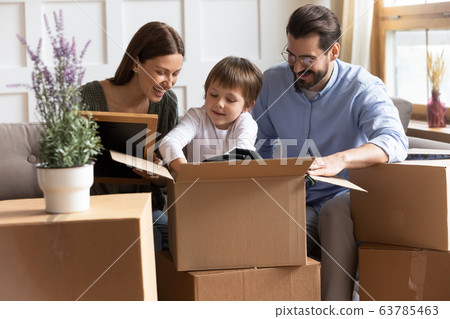Smiling small child boy unpacking things with parents. 63785463