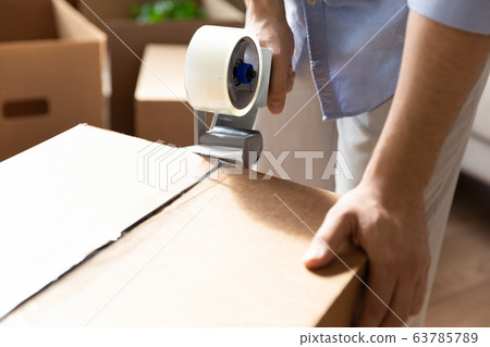 Close up young man packing stuff in cardboard box. Close up young man packing stuff in cardboard box. 63785789