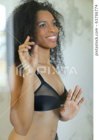 Portrait of black beautiful girl wearing bra and touching glass in bathroom. 63786774