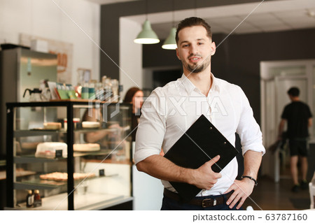 Young administrator standing with black folder at cafe. 63787160