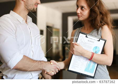 Young businessman shaking hands with female manager. Young businessman shaking hands with female manager. 63787162
