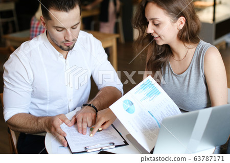 Young successful husband and wife working with documents. Young successful husband and wife working with documents. 63787171
