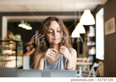 Young woman making video call by laptop at cafe. 63787186