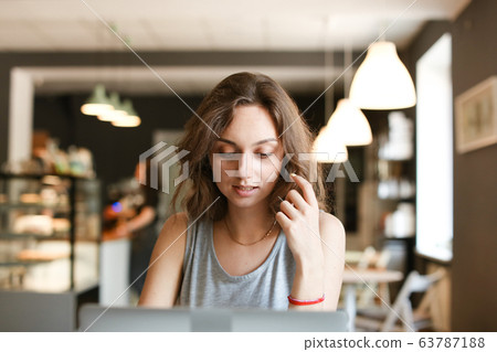 Female nice student working with laptop at cafe. Female nice student working with laptop at cafe. 63787188