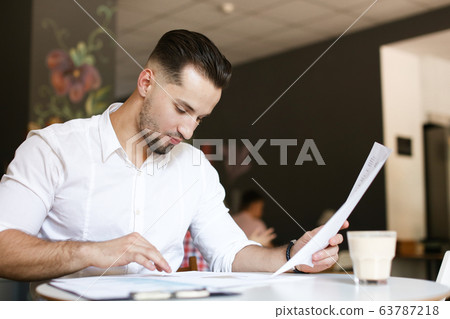 Young caucasian businessman working with documents at cafe. 63787218