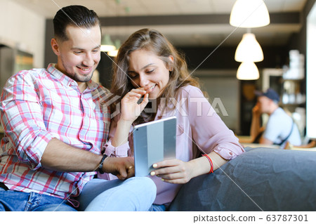 Young caucasian man and woman using tablet and free hotspot at cafe. 63787301