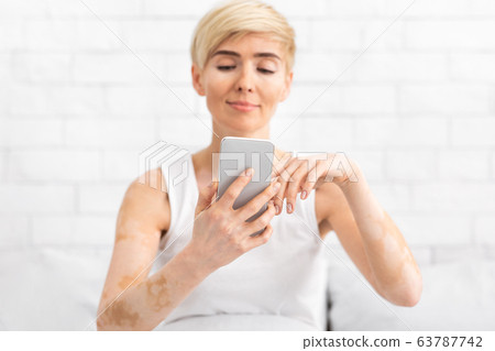 Cheerful middle aged lady texting on modern cellphone Cheerful middle aged lady texting on modern cellphone 63787742