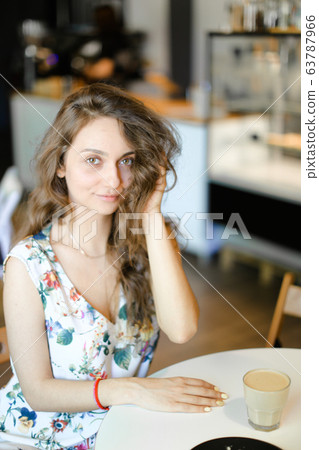 Young woman with cup of coffee sitting at cafe and resting. Young woman with cup of coffee sitting at cafe and resting. 63787966