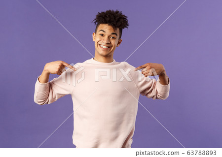 Cute and silly handsome male student pointing at himself and making lovely smile, ready to help offer himself, want participate or being chosen, volunteer to be a candidate, purple background 63788893