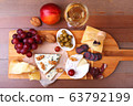 Assortment of cheese with fruits, grapes, nuts, glass with wine and cheese knife on a wooden serving tray. 63792199
