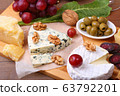 Assortment of cheese with fruits, grapes, nuts, glass with wine and cheese knife on a wooden serving tray. 63792201