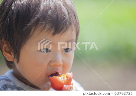 Boy eating tomato Boy eating tomato 63792725