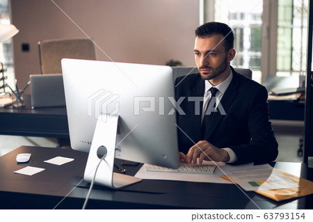 Caucasian calm businessman looking at screen of computer 63793154